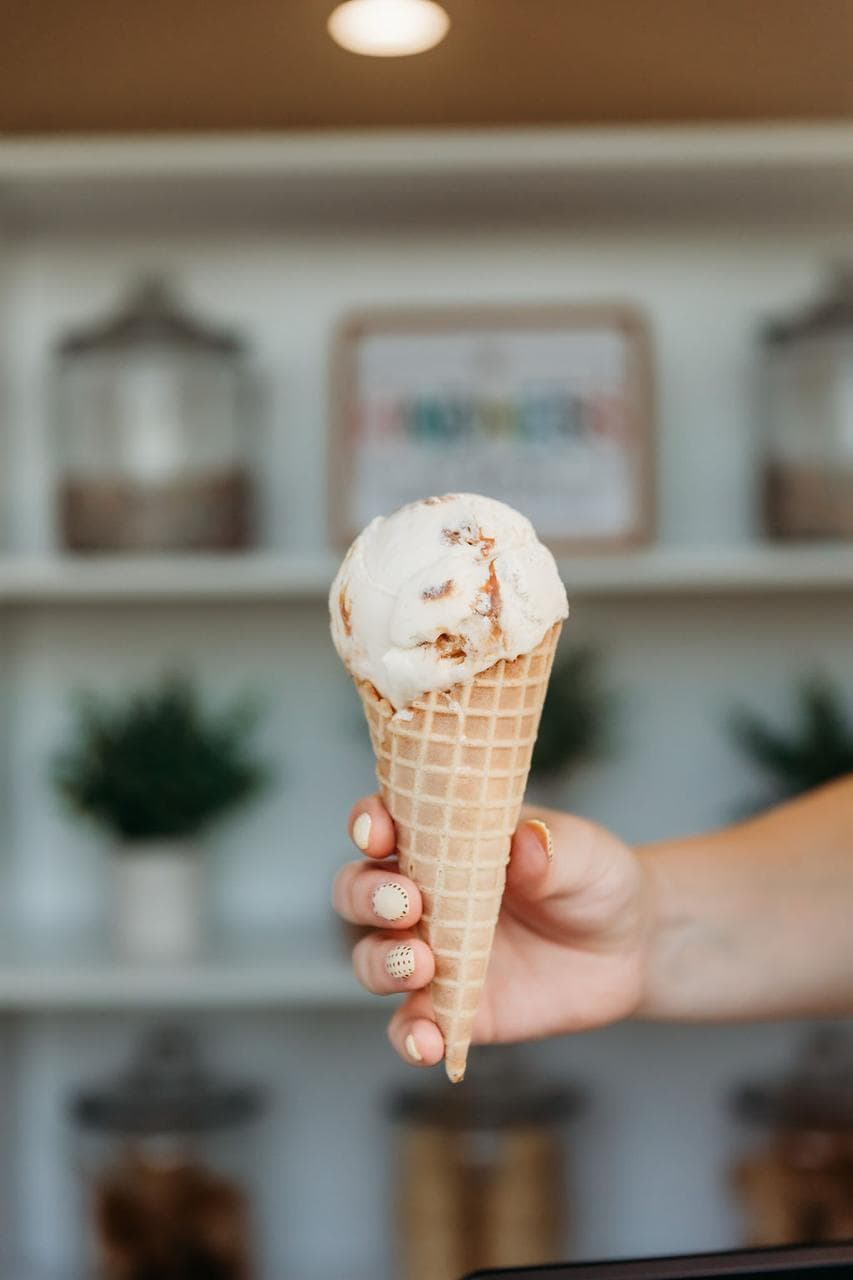A scoop of ice cream hand-dipped into a waffle cone.